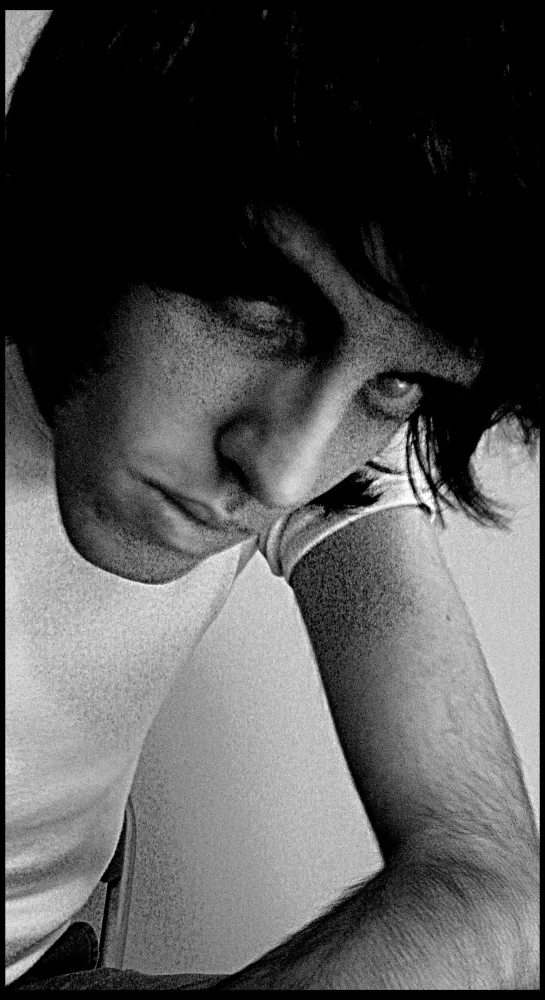 Grainy black-and-white self-portrait of the artist, his face half-hidden, resting on his arm